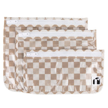 Load image into Gallery viewer, Roamio by Bumkins Clear Travel Bag 3 Pack: Sand Check includes 3 TSA-compliant pouches made of tan checkered waterproof fabric with zippers.