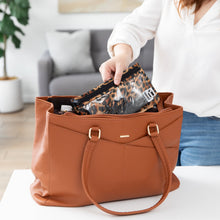 Load image into Gallery viewer, A person places a Roamio by Bumkins Clear Travel Bag 3 Pack: Leopard in a brown purse on a white table.