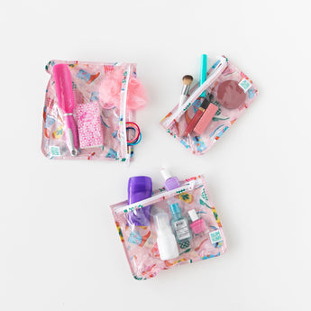 Bumkins Clear Travel Bag 3 Pack: Boots, TSA-compliant with colorful patterns, is displayed with makeup and toiletries on a white background.