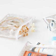 Load image into Gallery viewer, Close-up of Bumkins Clear Travel Bag 3-Pack: Wander on a white background with toiletries & hair accessories peeking out.