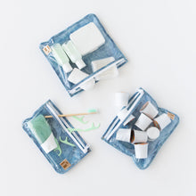 Load image into Gallery viewer, Roamio by Bumkins Clear Travel Bag 3 Pack: Crushed Denim holds toiletries and coffee pods on a white background.