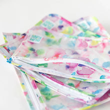Load image into Gallery viewer, Close-up of Bumkins Clear Travel Bag 3-Pack: Watercolor stacked on a white background, with the top back unzipped, revealing the interior.