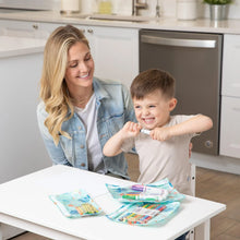 Load image into Gallery viewer, A woman and child sit at a white table in a kitchen with art supplies in Bumkins Clear Travel Bag 3-Pack: Ocean Life.