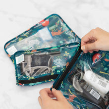 Load image into Gallery viewer, Hands unzip Bumkins Clear Travel Bag 3-Pack: Jungle filled with toiletries and makeup on a marble surface.