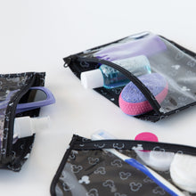 Load image into Gallery viewer, Close-up of Bumkins Clear Travel Bag 3-Pack: Mickey Mouse Icon Black + White filled with toiletries on a white background.