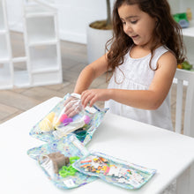 Load image into Gallery viewer, A girl reaches for craft supplies in Bumkins Clear Travel Bag 3 Pack: Aloha Stitch at a white table.