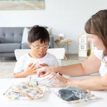 Load image into Gallery viewer, A child with glasses and an adult explore Bumkins Clear Travel Bag 3-Pack: Winnie and Friends on a white table in a cozy living room.