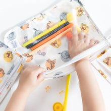 Load image into Gallery viewer, Close-up of a child's hands arranging colorful markers in a Bumkins Clear Travel Bag 3-Pack: Winnie and Friends on a white table.