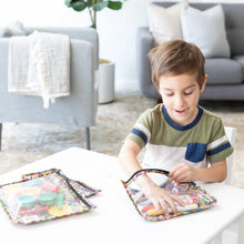 Load image into Gallery viewer, A child plays with markers and art supplies in Bumkins Clear Travel Bag 3-Pack: Super Mario™ Mashup at a white table in a cozy living room.