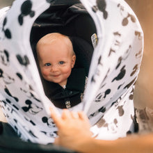 Load image into Gallery viewer, A smiling baby in a stroller with a Milk Snob Cover Disneys Mickey Sketch, gently pulled back by an adult hand.