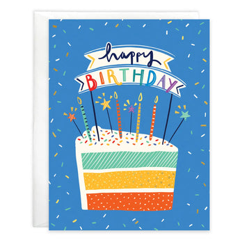Gina B Designs Birthday Card featuring a slice of layered cake with candles and a Happy Birthday banner on a blue confetti background.