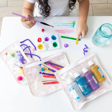 Load image into Gallery viewer, A child painting with colorful paints at a white table, while Bumkins Clear Travel Bag 3-Pack: Lace holds are supplies nearby.