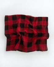 Load image into Gallery viewer, A Cotton Swaddle in red plaid by Little Unicorn is crumpled on a white surface.