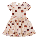 The Blake Birdie Dress by Birdie Bean features birthday cakes, candles, and a ruffled hem—perfect for any special moment.