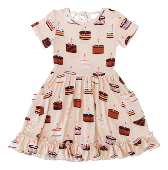 The Blake Birdie Dress by Birdie Bean features birthday cakes, candles, and a ruffled hem—perfect for any special moment.