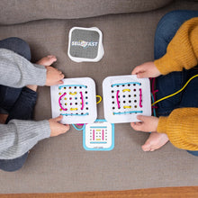 Load image into Gallery viewer, Two kids on a couch use colorful string to lace through boards from Fat Brain Toy Cos Sew Fast, excitedly following challenge cards.