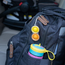 Load image into Gallery viewer, Gray backpack on car seat with colorful sippy cup in side pocket and Fat Brain Toy Cos clear Simpl Dimpl attached to the zipper.