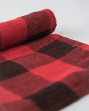 Load image into Gallery viewer, A rolled-up Cotton Swaddle in Red Plaid by Little Unicorn lies on a white background.