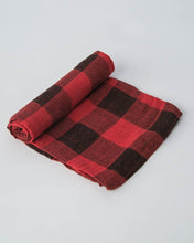 Load image into Gallery viewer, Partially rolled Little Unicorn red plaid cotton swaddle on a light gray background.