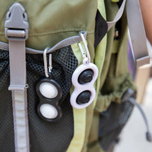 Load image into Gallery viewer, A black and white Simpl Dimpl from Fat Brain Toy Co offers tactile stimulation in a green backpacks gray mesh pocket.
