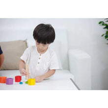 Load image into Gallery viewer, A child in a white shirt enhances color recognition playing with PlanToys Beehives at a bright table.
