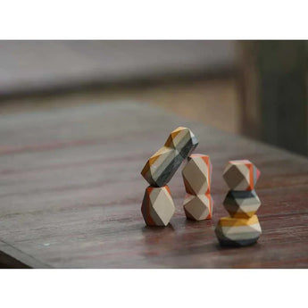 PlanToys Geo Stacking Rocks, colorful and sustainable, are great for developing fine motor skills on a wooden table.
