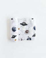 Lightweight cotton swaddle by Little Unicorn with space-themed prints of planets and stars. Folded neatly.