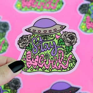 The Turtle Soup Stay Weird vinyl sticker features vibrant text, a hat, roses, hearts, and greenery held by a hand with black nails.