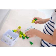 Load image into Gallery viewer, A child assembles a green piece PlanToys Balancing Cactus Mini from sustainably made wood. Box includes instructions.
