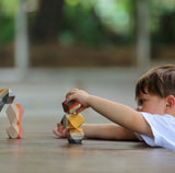 A child hones motor skills outdoors with PlanToys Geo Stacking Rocks, made from sustainable materials.