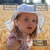 Young child in a wheat field wearing the Bumkins Sun Hat, Pink—adjustable with break-away safety clip and UPF 50+ cotton.