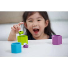 Load image into Gallery viewer, A child enhances motor skills with PlanToys Beehives, exploring colorful blocks and round objects on a white surface.
