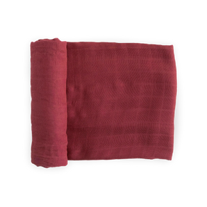 Deluxe Muslin Swaddle in Dusty Maroon by Little Unicorn, folded with a grid pattern and partially rolled on a white background.