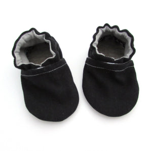 Cabooties Denim Black baby shoes with elastic ankle closure and white stitching on a white background.