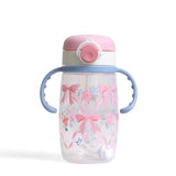 The Itzy Ritzy Itzy Sips Ribbons & Roses cup is clear with blue handles, a pink lid, and pink bows and flowers on the front.