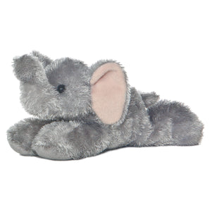 Aurora Mini Flopsie Ellie, a plush elephant with big pink ears, lies on its stomach facing left against a white background.
