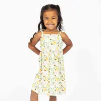 Load image into Gallery viewer, A young girl smiling in an Emerson and Friends Sundress with the Happy Honey Bees pattern, hands on hips, against a white backdrop.
