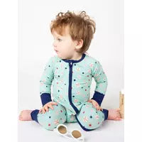A young child in an Emerson and Friends Sleeper, Baseball Buddies onesie with a two-way zipper sits on the floor near sunglasses.