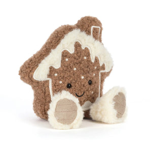 A smiling Jellycat Amuseables Molasi cookie plush shaped like a gingerbread house with fuzzy white trim.