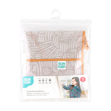 Load image into Gallery viewer, Bumkins Long-Sleeved Art Smock: Wander is shown folded in plastic packaging bag with a hanger and cardboard insert.
