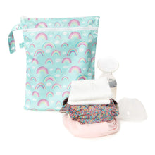 Load image into Gallery viewer, Bumkins Wet/Dry Bag: Rainbows sits by a stack of cloth diapers and a breast pump on a white background.
