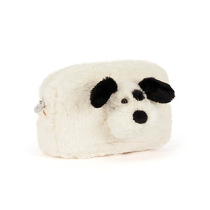 A cream-colored, fuzzy Jellycat Pouch Rufferty Puppy shaped like a playful puppy with black ears, a black nose, and a black eye patch.