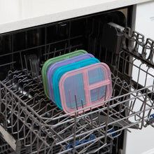 Load image into Gallery viewer, Four lids, including one from Bumkins Silicone Bento Box 3 Section: Green Jelly, sit in the top rack of an open dishwasher.
