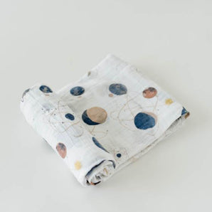 The Little Unicorn Cotton Swaddle, Planetary features hand-painted space-themed prints of planets and stars on light gray cotton muslin.