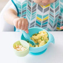 Load image into Gallery viewer, Close-up of a baby eating scrambled eggs and avocado from a Bumkins Silicone First Feeding Set: Blue, with cereal puffs in a green cup.
