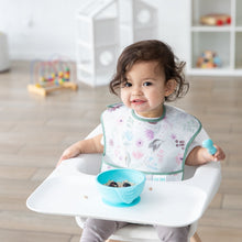 Load image into Gallery viewer, A toddler in a high chair wears a floral bib, eating oatmeal and berries from a Bumkins Silicone First Feeding Set: Blue in a bright room.
