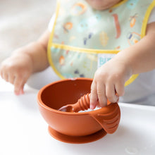Load image into Gallery viewer, Close-up of a baby in a bib eating yogurt from Bumkins Silicone First Feeding Set: Clay on a high chair tray.
