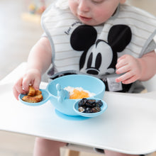 Load image into Gallery viewer, A toddler uses the Bumkins Silicone First Feeding Set: Mickey Mouse Light Blue to eat snacks on their highchair.
