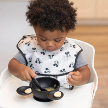 Load image into Gallery viewer, A toddler in a high chair enjoys bananas and applesauce from a Bumkins Silicone First Feeding Set: Mickey Mouse Classic Black.
