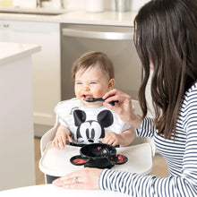 Load image into Gallery viewer, An adult feeds grinning baby in a high chair from a Bumkins Silicone First Feeding Set: Mickey Mouse Classic Black.
